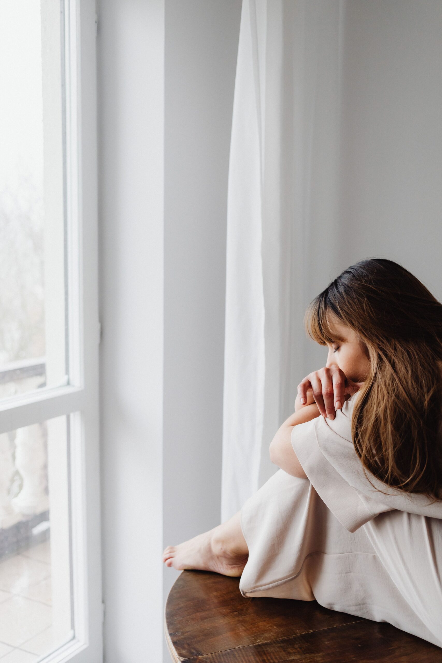 Mujer sentada junto a una ventana creando un espacio de pausa y recuperación
